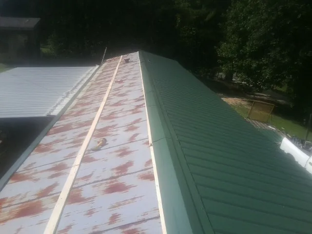 Old rusted panels beside newly installed green metal roofing — Wind Damage Roof Repair by Roofing Brothers in Moultrie