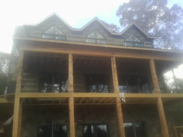 Dormers and porch framing on a large log home under construction — Roof Coating work by our crew in Moultrie