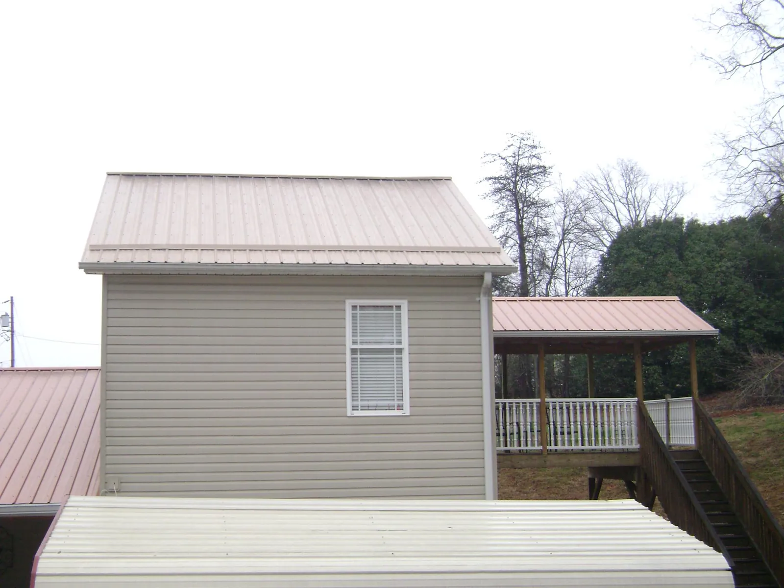 Tan metal roofs on a two story addition and attached porch, from a Roof Replacement job in Moultrie