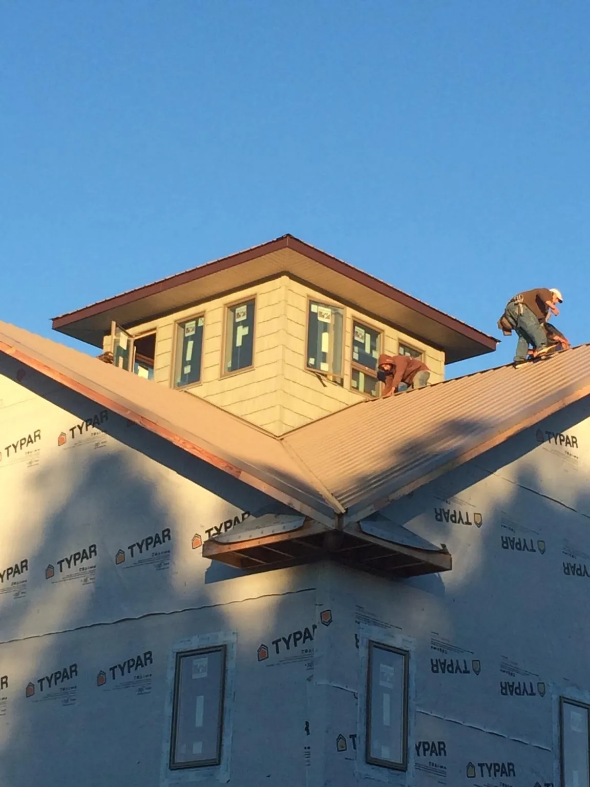 Roofers working around a rooftop cupola on a new metal roof at sunset — Roof Waterproofing in Moultrie by Roofing Brothers